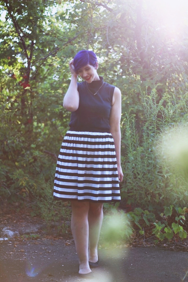 Outfit: Striped skirt, black sleeveless mock turtleneck, dainty gold necklace, black flats, purple pixie cut